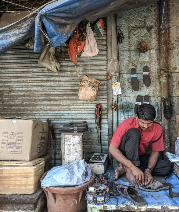 a man is working on a pair of shoes, by Scott Samuel Summers, pexels contest winner, assemblage, streets of mumbai, thumbnail, sitting on a store shelf, tools and junk on the ground