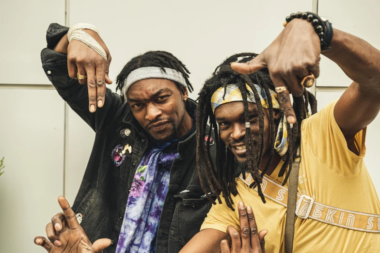 a couple of men standing next to each other, unsplash, black arts movement, short dreadlocks with beads, concert photo, space dandy style, fists in the air