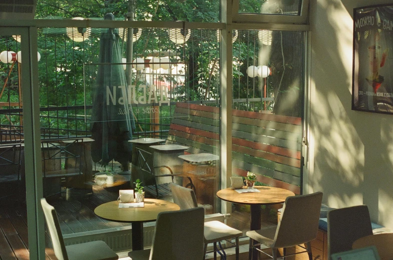 a restaurant with a lot of tables and chairs, a photo, unsplash, art nouveau, against the backdrop of trees, filtered light, 2 0 0 0's photo, neo kyiv