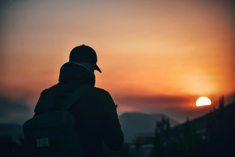 a person with a backpack looking at the sunset, pexels contest winner, profile shot, subtle detailing, over his shoulder, dark. no text