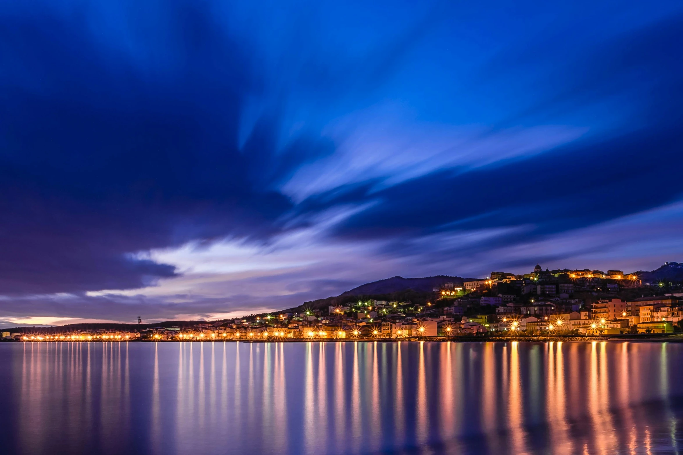 a large body of water under a cloudy sky, a picture, pexels contest winner, romanticism, distant town lights, split near the left, blue reflections, wellington