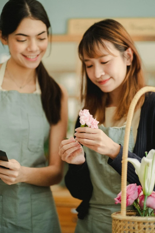 a couple of women standing next to each other, trending on pexels, renaissance, japanese flower arrangements, checking her phone, wearing an apron, product introduction photos