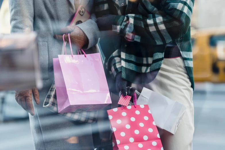 a woman talking on a cell phone while holding shopping bags, a photo, by Julian Hatton, pexels contest winner, shopwindows, pink, hands pressed together in bow, male and female