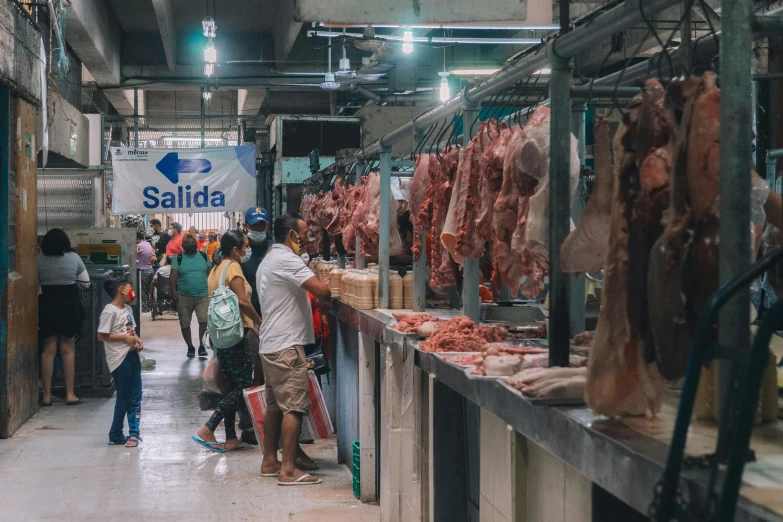 a group of people standing around a food market, by Alejandro Obregón, pexels contest winner, hyperrealism, hanging beef carcasses, square, thumbnail, mall