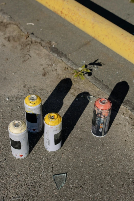 a couple of spray cans sitting on the side of a road, a picture, high shadow, r / paintedminis, high damage, in a row