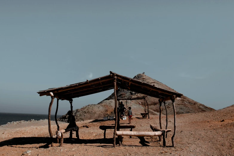 a wooden shelter sitting on top of a sandy beach, pexels contest winner, les nabis, mining outpost, benches, thumbnail, mecca