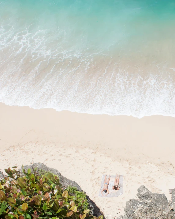 a couple of people laying on top of a sandy beach, pexels contest winner, minimalism, lush surroundings, thumbnail, overlooking the ocean, flatlay