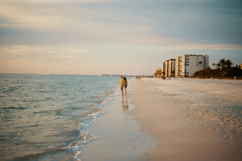 a person walking on a beach next to the ocean, beachfront, multiple stories, florida, sunfaded