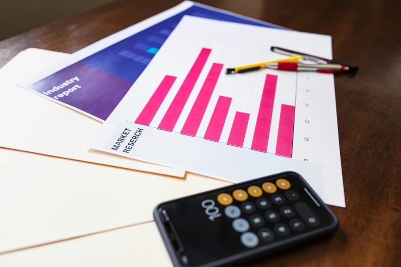 a wooden table topped with papers and a calculator, a digital rendering, pexels, analytical art, purple tubes, realistic »