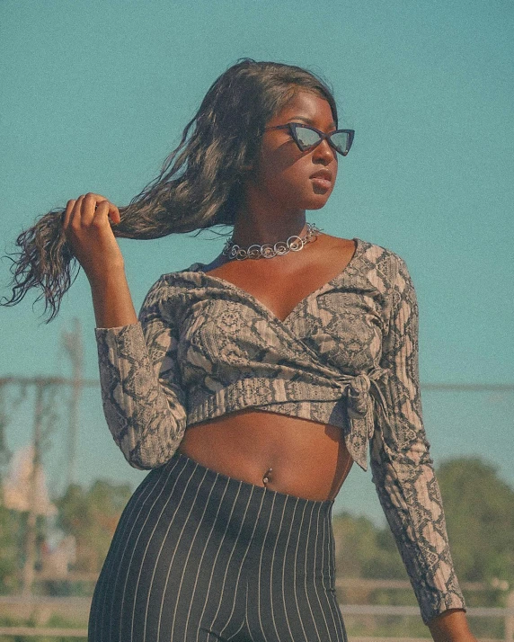 a woman in a snakeskin top and leggings, by Byron Galvez, trending on pexels, black teenage girl, beautiful midriff, shades, old fashion