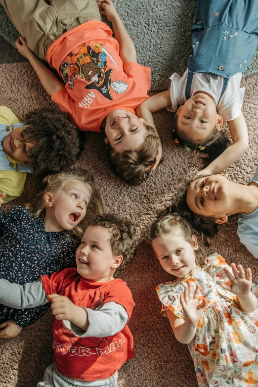 a group of children laying on the floor in a circle, smiling down from above, slide show, gen z, extra high resolution