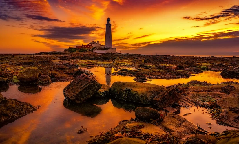 a lighthouse sitting on top of a rocky beach, by Jay Hambidge, pexels contest winner, romanticism, golden hour 8k, yorkshire, vibrant orange, 🦩🪐🐞👩🏻🦳