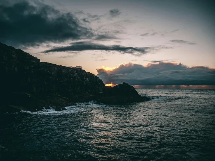 a large body of water under a cloudy sky, an album cover, pexels contest winner, cliff side at dusk, high quality photo, coastal, dark and forboding