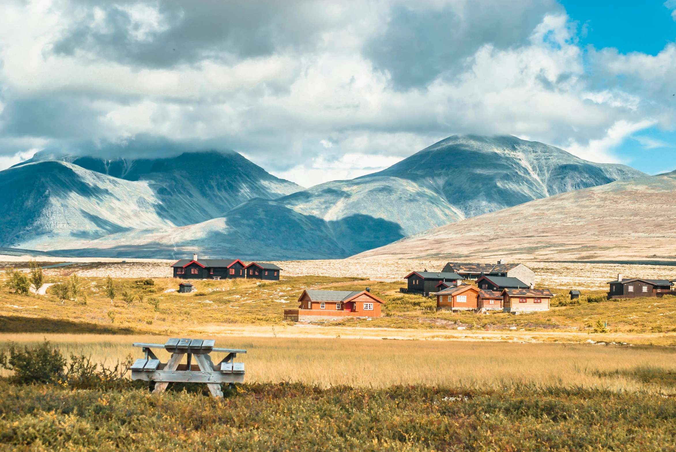 a picnic table in a field with mountains in the background, by Jesper Knudsen, hurufiyya, several cottages, outworldly colours, tundra, instagram photo