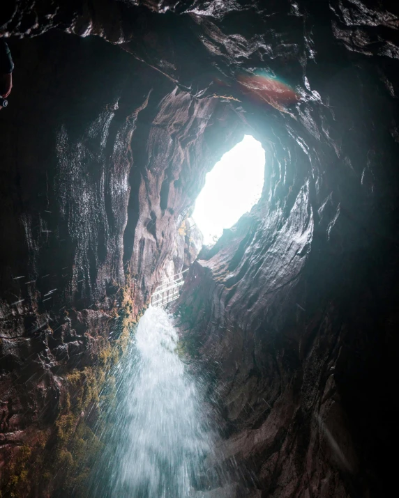 the inside of a cave with water coming out of it, shallan davar, volcanic, overhead, high light on the left