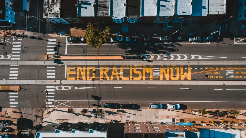 a street filled with lots of traffic next to tall buildings, by Carey Morris, trending on unsplash, renaissance, protesters holding placards, black and yellow scheme, any racial background, wide aerial shot