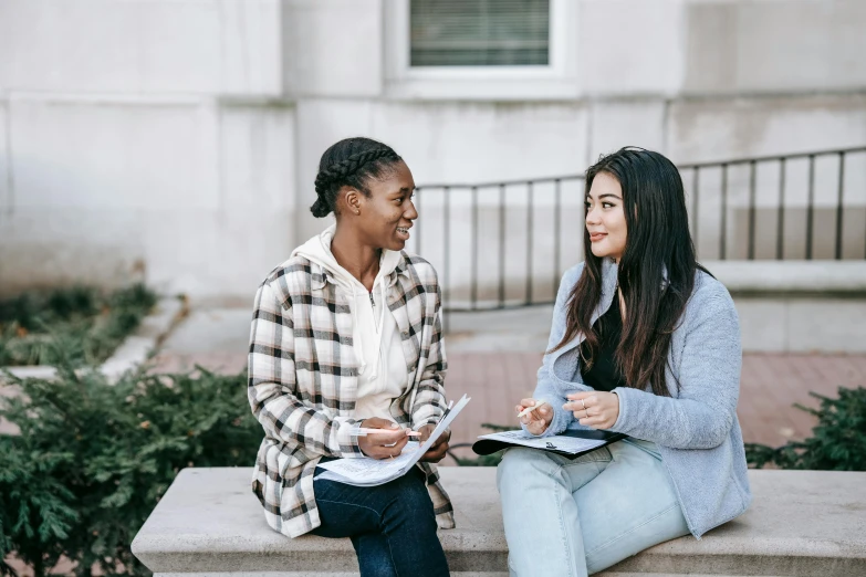 two women sitting on a bench talking to each other, trending on pexels, academic art, background image, college students, thumbnail, 1 2 9 7