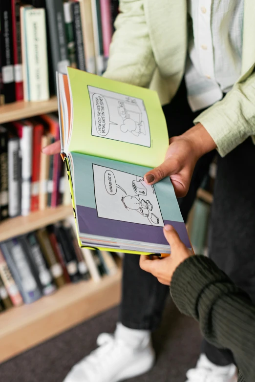 two people holding books in front of a bookshelf, a cartoon, by Dan Content, pexels, happening, colour photograph, comic book panel, on display, interior of a library