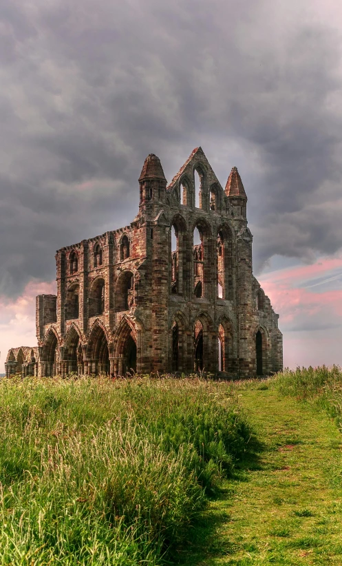 a large stone building sitting on top of a lush green field, pexels contest winner, romanesque, in ruin gothic cathedral, against a stormy sky, panoramic, pink