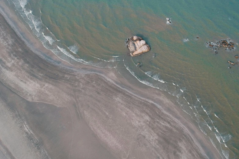 a couple of rocks sitting on top of a sandy beach, an album cover, pexels, land art, aerial view cinestill 800t 18mm, derelict space ship, zezhou chen, very beautiful!! aerial shot