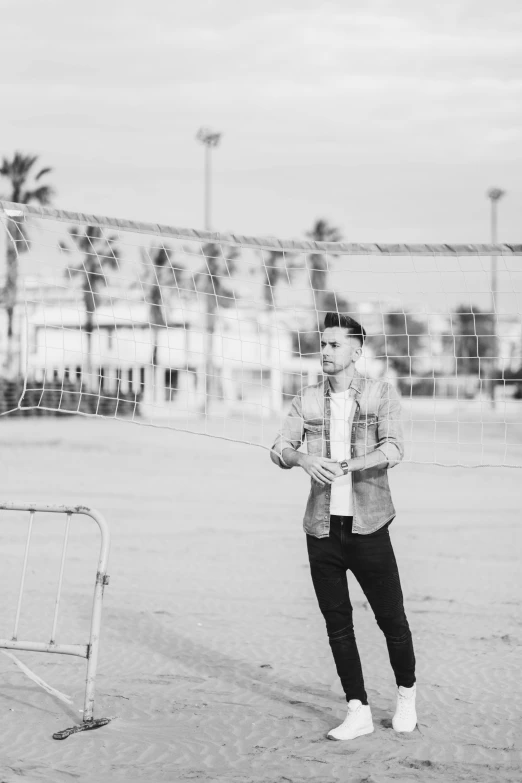 a black and white photo of a man holding a frisbee, a black and white photo, inspired by Menez, pexels contest winner, zayn malik, playing soccer at the beach, standing astride a gate, netting