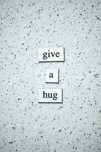 a sign that says give a hug on a concrete wall, inspired by Muggur, unsplash, profile image, white, magnetic, concrete poetry