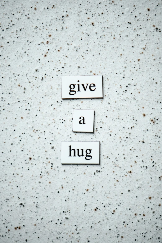 a sign that says give a hug on a concrete wall, inspired by Muggur, unsplash, profile image, white, magnetic, concrete poetry