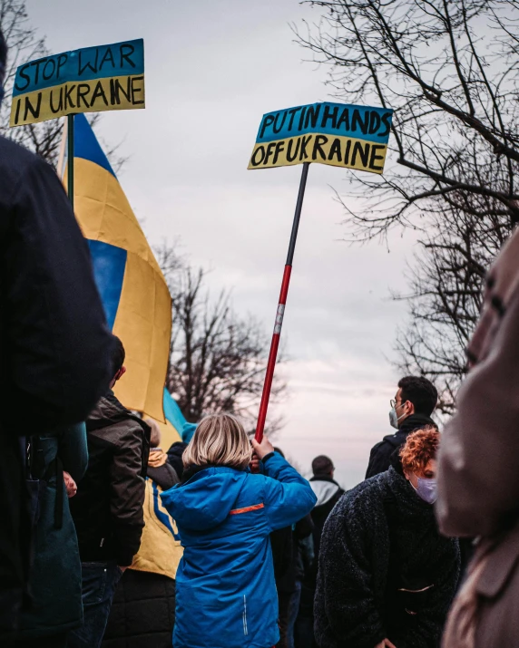 a group of people standing next to each other holding signs, by Matija Jama, trending on unsplash, antipodeans, ukrainian flag on the left side, instagram story, yellow and blue ribbons, oktane