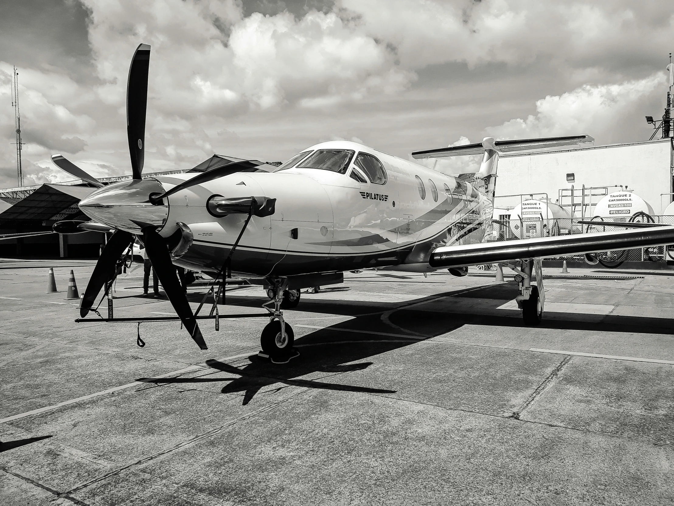 a small propeller plane sitting on top of an airport tarmac, a black and white photo, by Reuben Tam, pexels contest winner, photorealism, sardax, beautiful daylight, super high resolution, powerful and huge