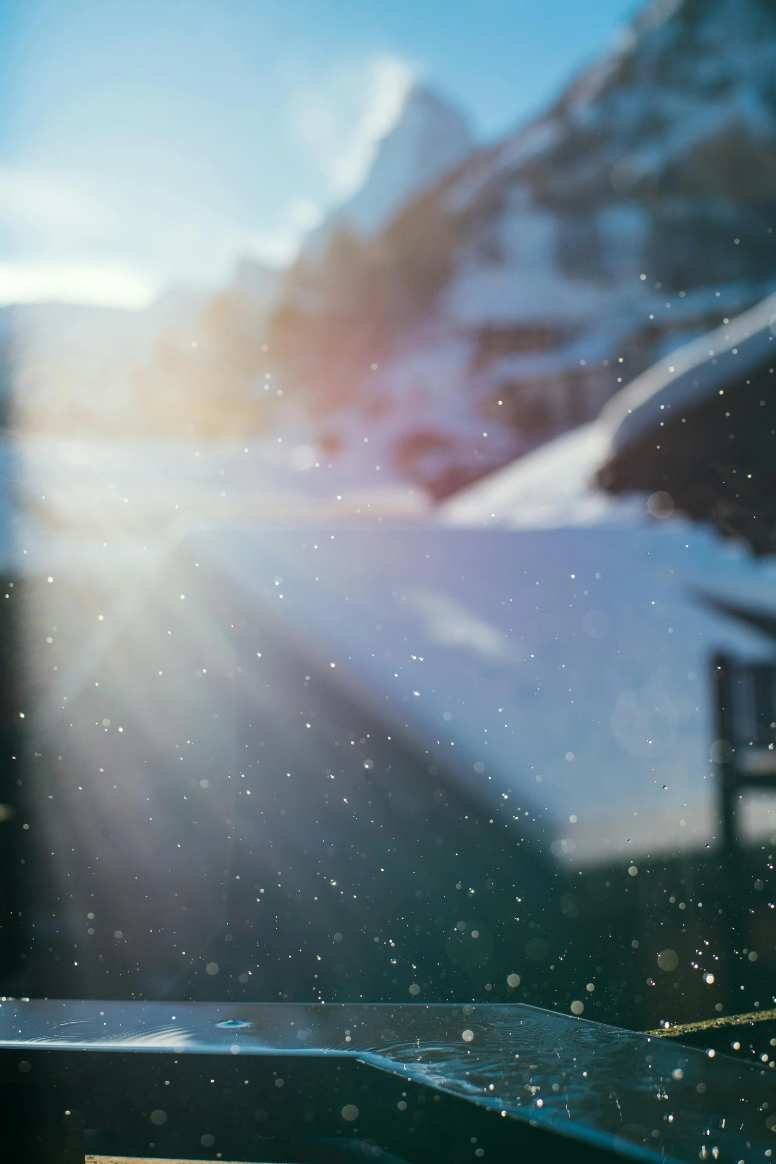 a pair of skis sitting on top of a snow covered slope, pexels contest winner, light and space, light breaks through the roofs, anamorphic bokeh and lens flares, god rays pass through the window, sun shines down on the car