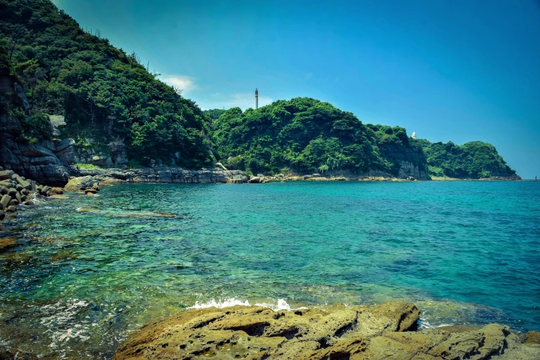 a body of water with a lighthouse in the background, unsplash, sōsaku hanga, beach is between the two valleys, 2 0 0 0's photo