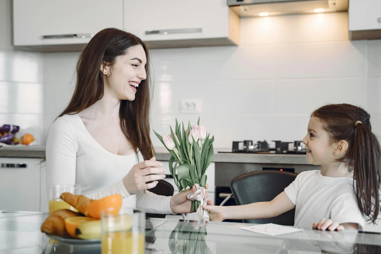 a woman and a little girl sitting at a kitchen table, pexels contest winner, holding flowers, avatar image, sleek design, high quality image