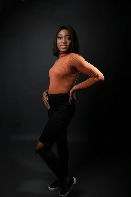 a woman standing in the dark with her hands on her hips, by Robbie Trevino, portrait of maci holloway, in a photo studio, orange and black, professional profile photo