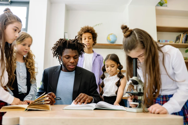 a group of children standing around a table looking at a book, pexels contest winner, future coder man looking on, varying ethnicities, teacher, professional picture