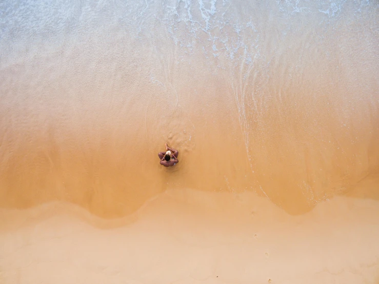 a man standing on top of a sandy beach next to the ocean, pexels contest winner, minimalism, a woman floats in midair, top down view, sandy colors, australian