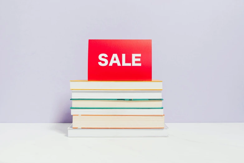 a pile of books with a sale sign on top, a stock photo, trending on unsplash, magic realism, on a pale background, background image, in style of ren hang, three - quarter view