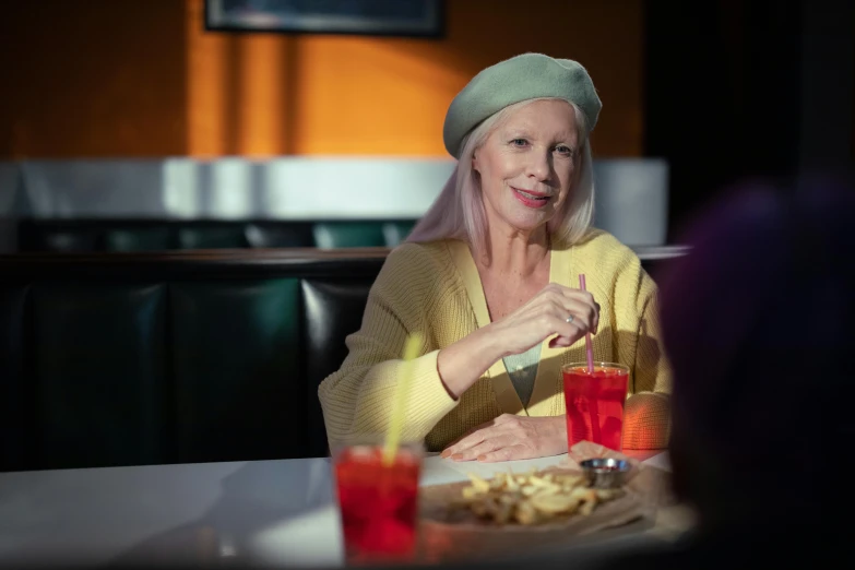 a woman sitting at a table with a plate of food, with long white hair, hollywood standard, wearing a french beret, lynn skordal