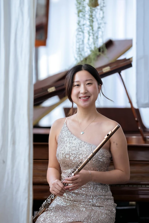 a woman sitting in front of a piano holding a flute, leslie zhang, on a pale background, portrait image, looking happy