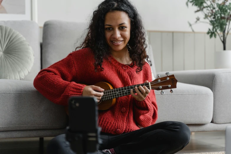 a woman sitting on the floor playing a guitar, pexels contest winner, hurufiyya, avatar image, ukulele, while smiling for a photograph, youtube thumbnail