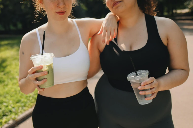 two women standing next to each other holding drinks, trending on pexels, cottagecore!! fitness body, green and black, obese, aussie baristas