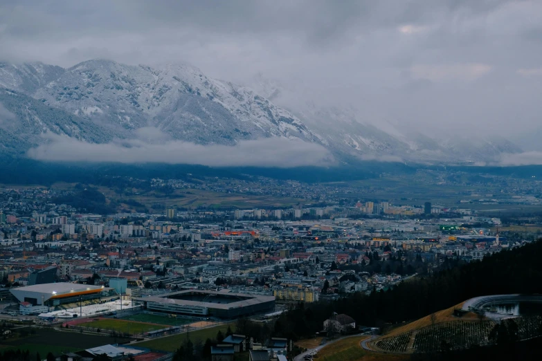 a view of a city with a mountain in the background, by Johannes Voss, pexels contest winner, cloudy day, alpine, low quality footage, high view