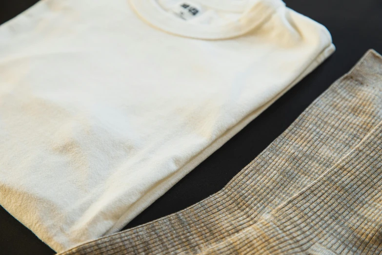 a pair of socks and a t - shirt on a table, inspired by Ogata Kōrin, unsplash, ecru cloth, worn pants, golden and silver colors, fine texture detail