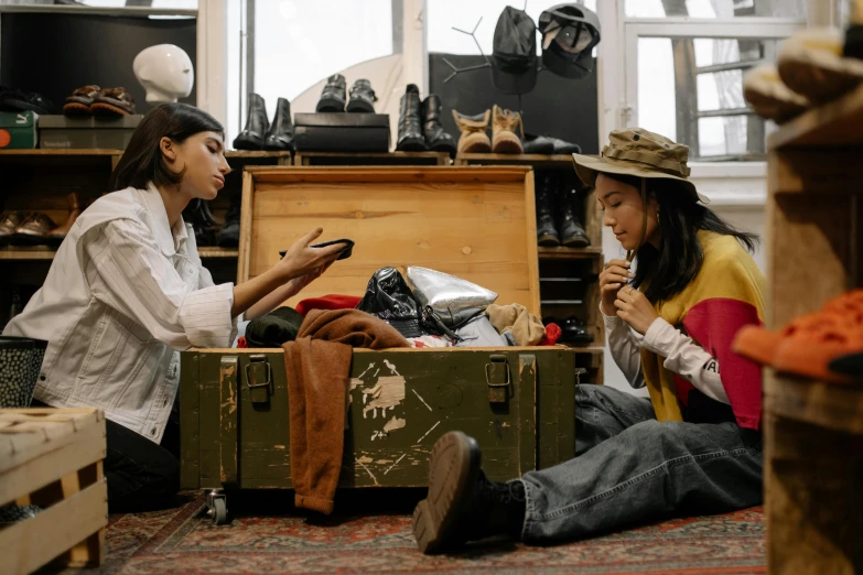 a couple of women sitting next to each other on the floor, pexels contest winner, art & language, in suitcase, inspect in inventory image, costume design made with love, adventure gear