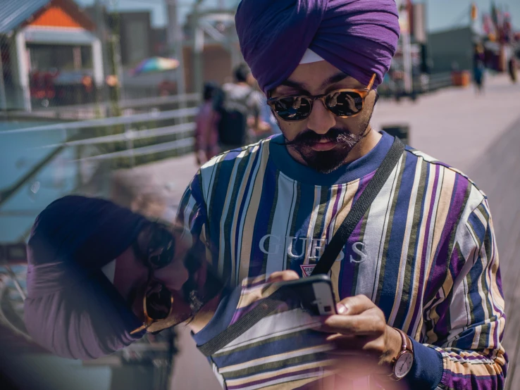 a man in a turban looking at his cell phone, inspired by Manjit Bawa, trending on pexels, purple outfit, gta v street style, teddy fresh, wearing shades