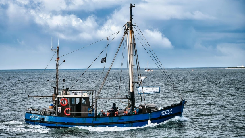 a blue boat traveling across a large body of water, by Niels Lergaard, pexels contest winner, fishing boat, mary anning, customers, three masts