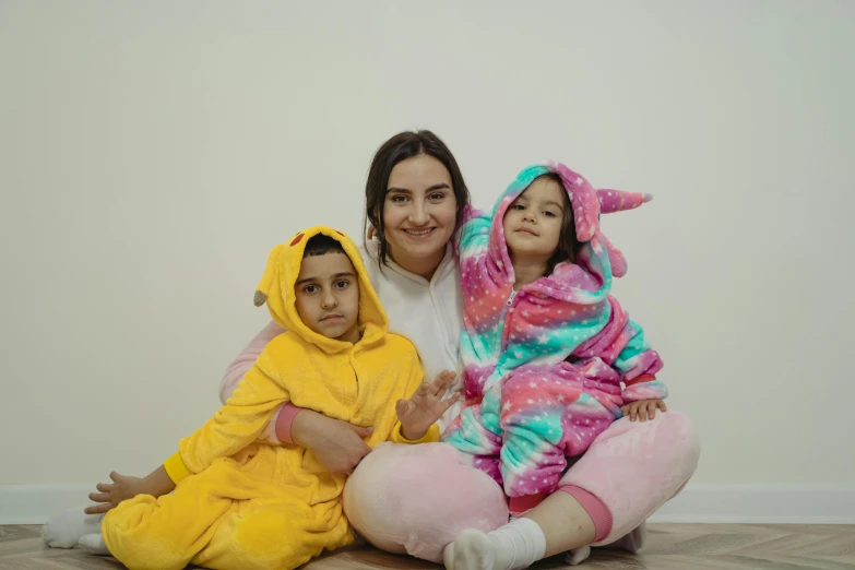a woman sitting on the floor with two children, by Charly Amani, pexels contest winner, hurufiyya, wearing a bunny suit, wearing a baggy pajamas, turkish and russian, thicc