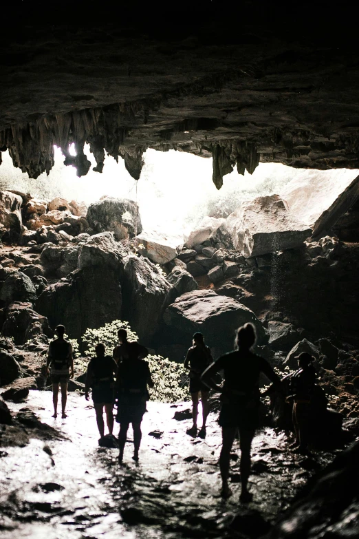 a group of people walking through a cave, tamborine, beautifully daylight, from the distance, black