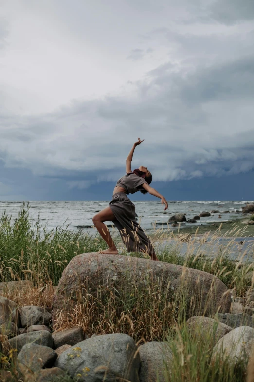 a man riding a bike on top of a rocky beach, by Robert Storm Petersen, unsplash, conceptual art, girl dancing on cliff, during a thunderstorm, kalevala, classic dancer striking a pose