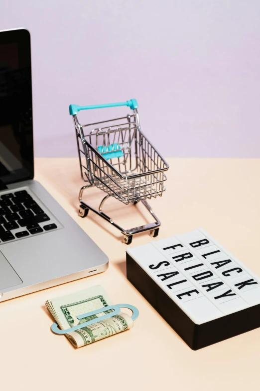 a laptop computer sitting on top of a desk next to a shopping cart, by Julia Pishtar, thumbnail, epicurious, black main color, full frame image