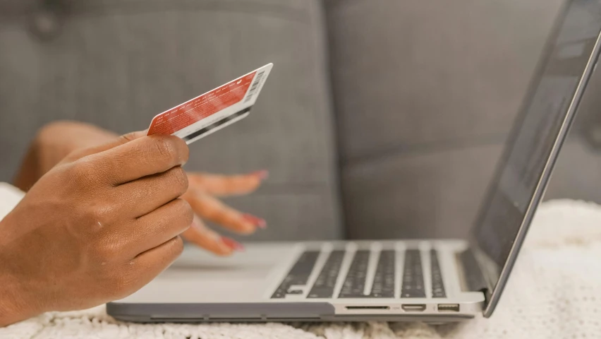 a person holding a credit card in front of a laptop, by Carey Morris, pexels contest winner, photo of a black woman, performing, garnishment, instagram post